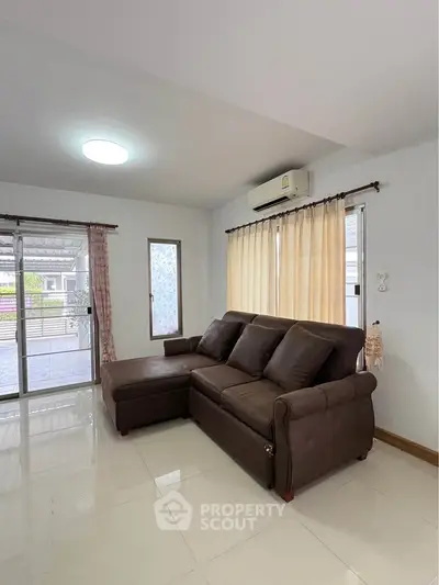 Spacious living room with modern brown sofa and large windows for natural light.