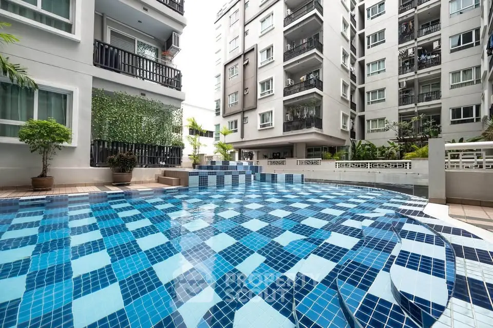 Modern apartment complex with a stylish outdoor pool and lush greenery.