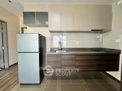 Modern kitchen with sleek cabinetry and stainless steel fridge in a contemporary apartment.