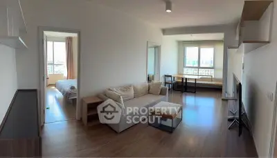 Spacious modern living room with natural light and city view, featuring a cozy sofa and sleek wooden flooring.