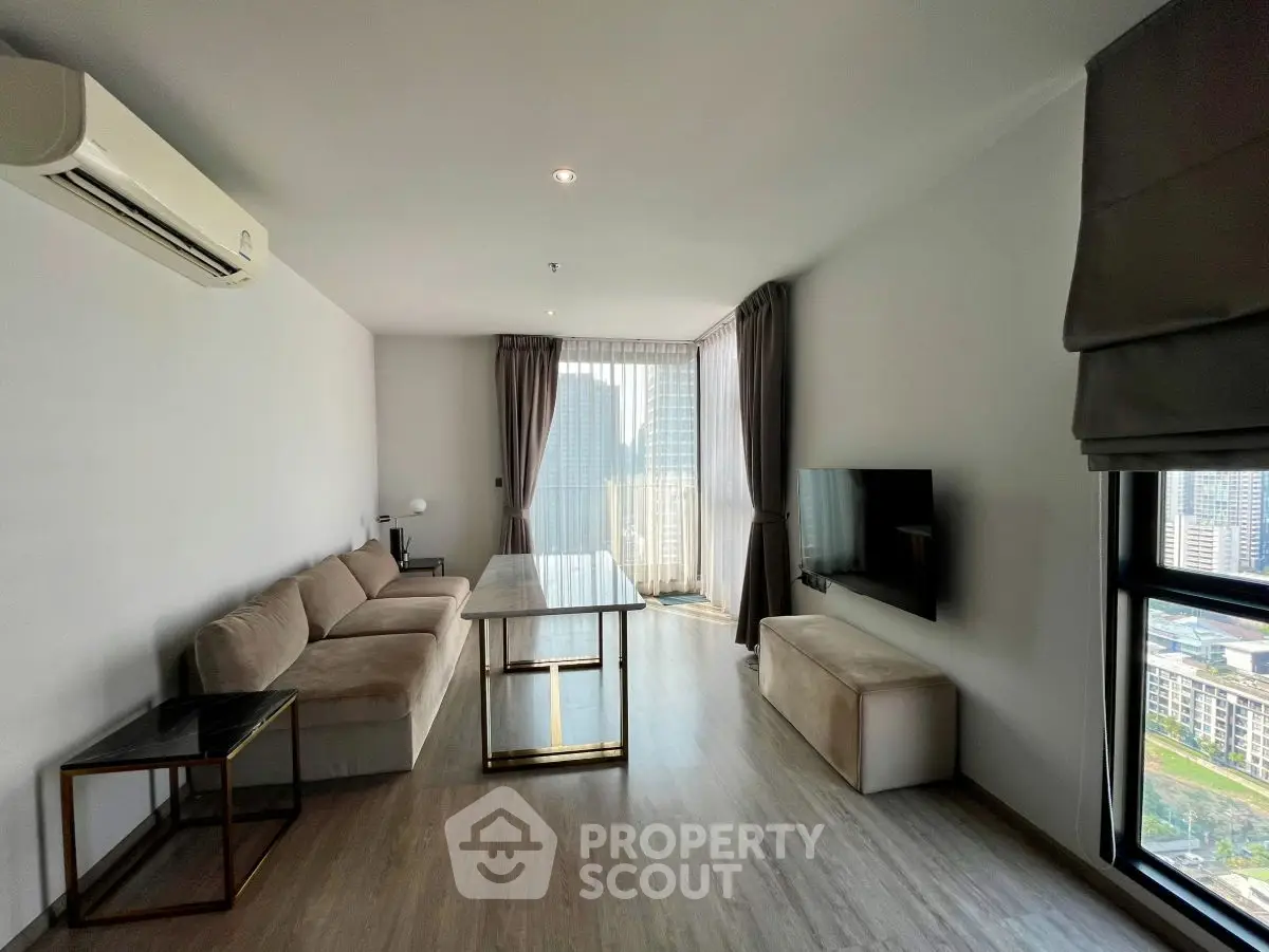 Modern living room with city view, featuring sleek furniture and large windows for natural light.