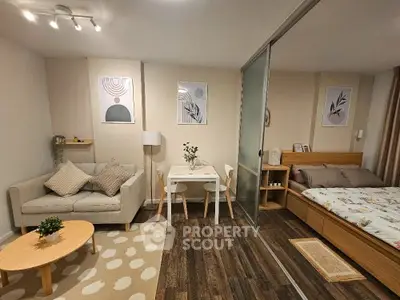 Cozy studio apartment with modern decor, featuring a living area and bedroom separated by sliding doors.