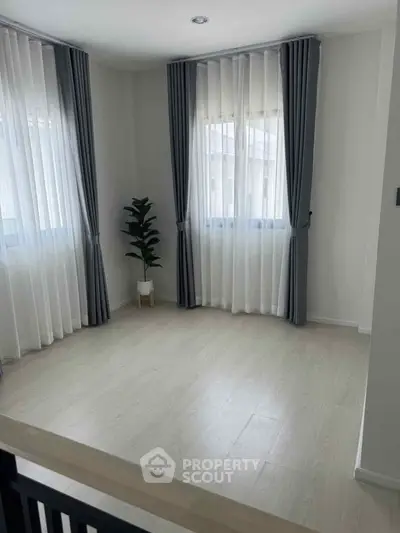 Bright and airy room with large windows and elegant curtains, perfect for a cozy living space.