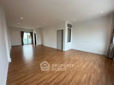 Spacious open-plan living room with wooden flooring and ample natural light.