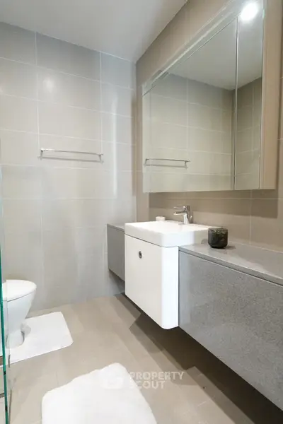 Modern bathroom with sleek design and large mirror, featuring elegant fixtures and neutral tones.
