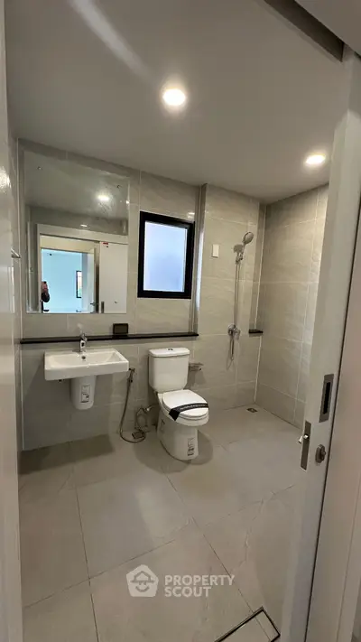 Modern bathroom with sleek fixtures and spacious layout, featuring a large mirror and elegant tiling.