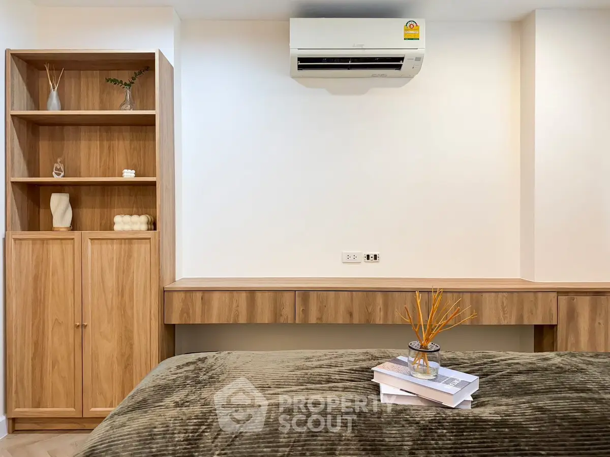 Modern bedroom with sleek wooden furniture and air conditioning unit.