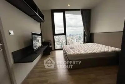 Modern bedroom with city view, featuring sleek design and large window for natural light.