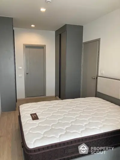 Modern bedroom with stylish grey accents and comfortable mattress in a contemporary apartment.