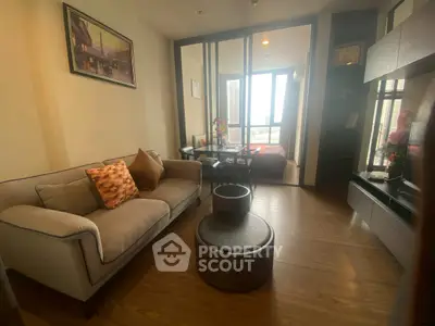 Cozy living room with modern decor and a view into the bedroom, featuring wooden flooring and stylish furniture.