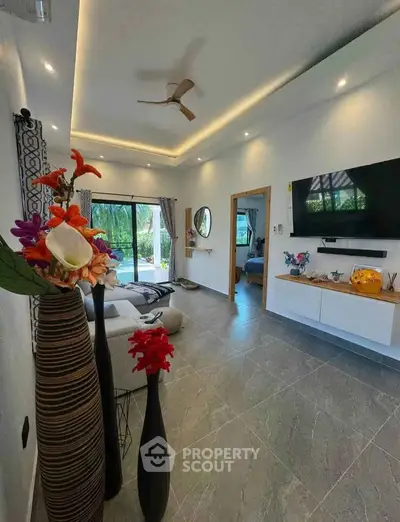 Spacious living room with modern decor, large TV, and garden view, perfect for relaxation and entertainment.