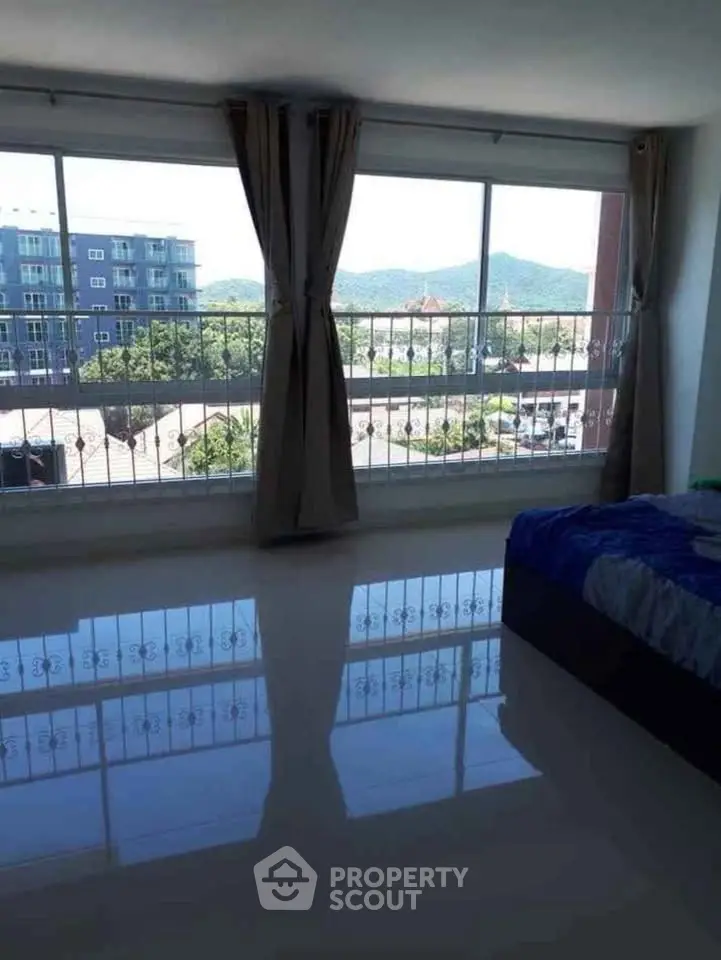 Spacious bedroom with large windows offering stunning city and mountain views.