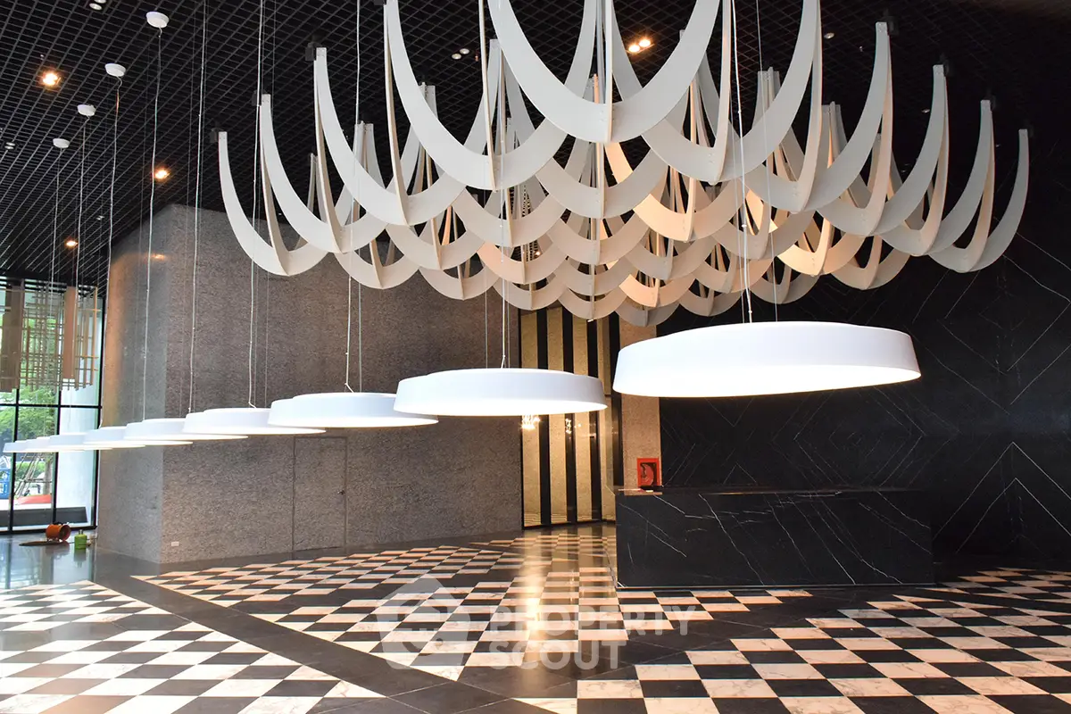 Luxurious modern building entrance with striking chandelier and elegant checkered flooring.