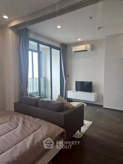 Modern living room with balcony, featuring sleek furniture and natural light.