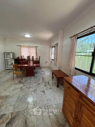 Spacious living room with marble flooring and large windows, featuring dining table and chairs, perfect for family gatherings.