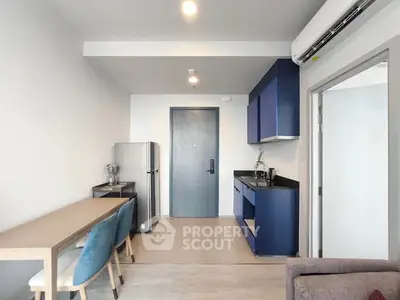Modern apartment interior with sleek kitchen and dining area, featuring blue cabinetry and contemporary design.