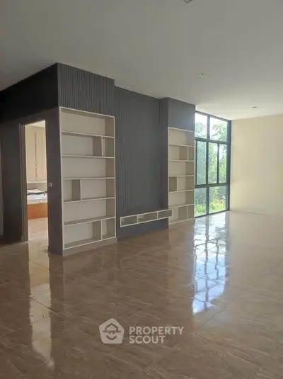 Spacious modern living room with large windows and built-in shelving, offering abundant natural light.
