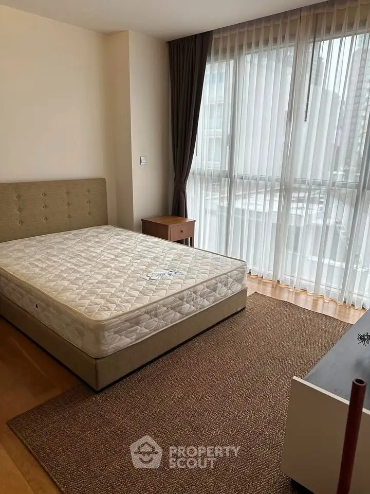 Spacious bedroom with large windows and natural light in modern apartment.