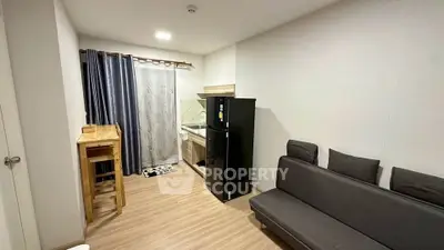 Modern studio apartment with compact kitchen and cozy living area, featuring sleek black fridge and stylish decor.