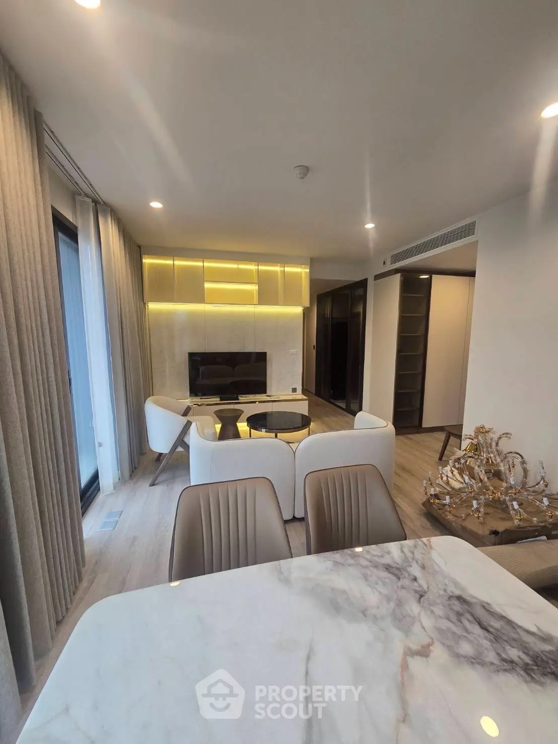 Luxurious modern living room with elegant marble dining table and cozy seating area.