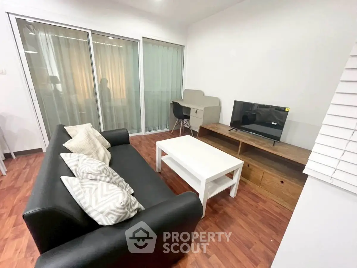 Modern living room with sleek black sofa, white coffee table, and TV on wooden stand, featuring stylish decor.