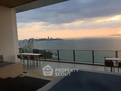 Luxurious balcony with stunning ocean view and modern outdoor seating at sunset.