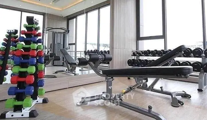 Modern gym with state-of-the-art equipment and panoramic windows in luxury building.