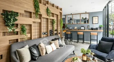 Chic modern living room with lush greenery, stylish furniture, and open-plan layout leading to a sleek breakfast bar.