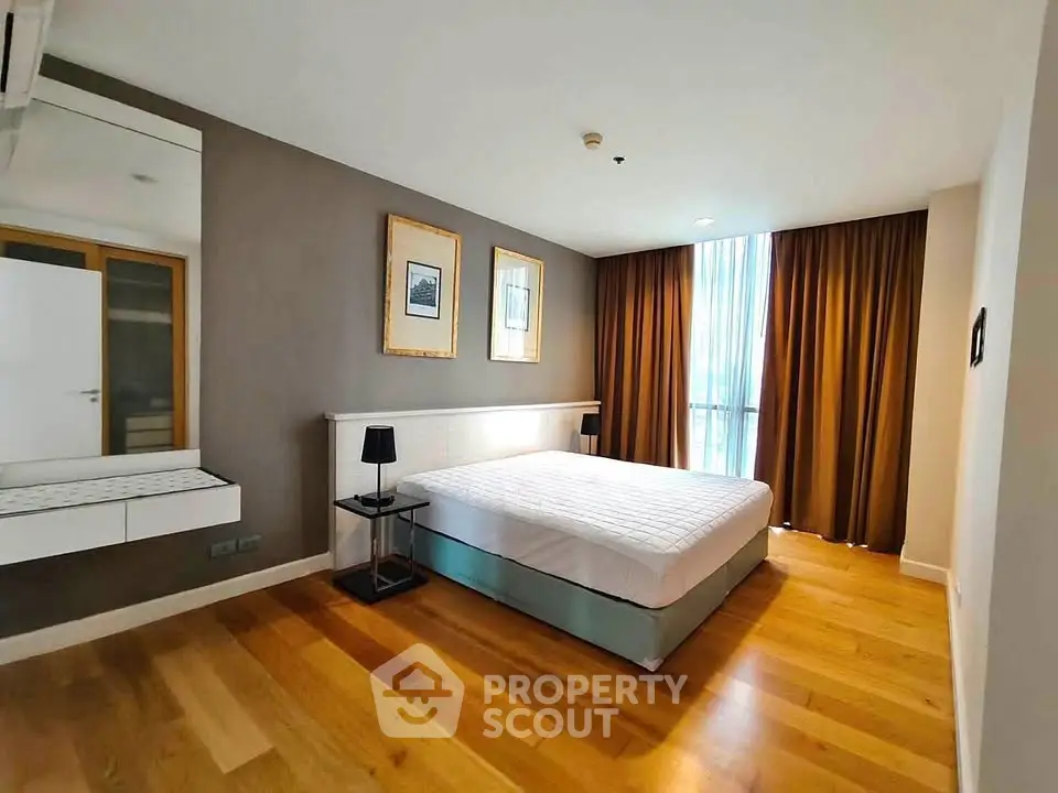 Spacious bedroom with modern decor and large window in a stylish apartment.
