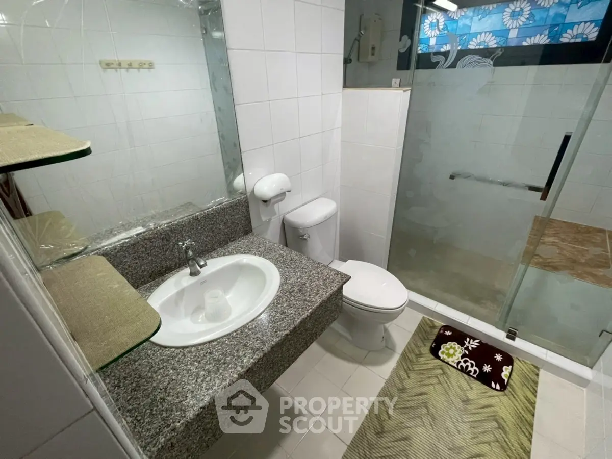 Modern bathroom with glass shower and granite countertop in stylish home.