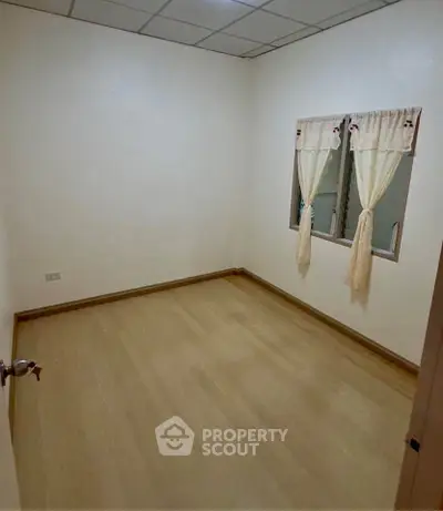 Cozy empty bedroom with wooden flooring and window curtains, perfect for customization.