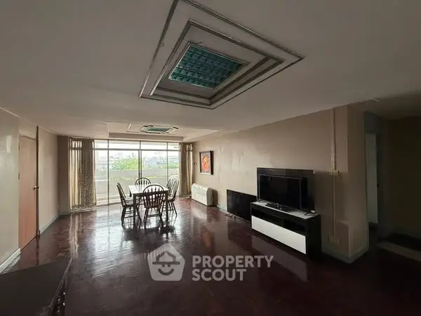 Spacious living room with dining area and large windows offering natural light.