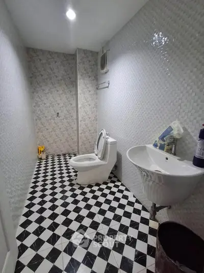 Modern bathroom with checkered floor tiles and sleek fixtures in a contemporary real estate property.