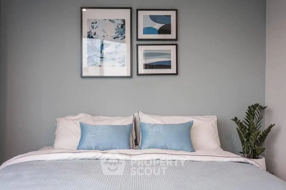 Stylish bedroom with modern decor and framed art on a serene blue wall.