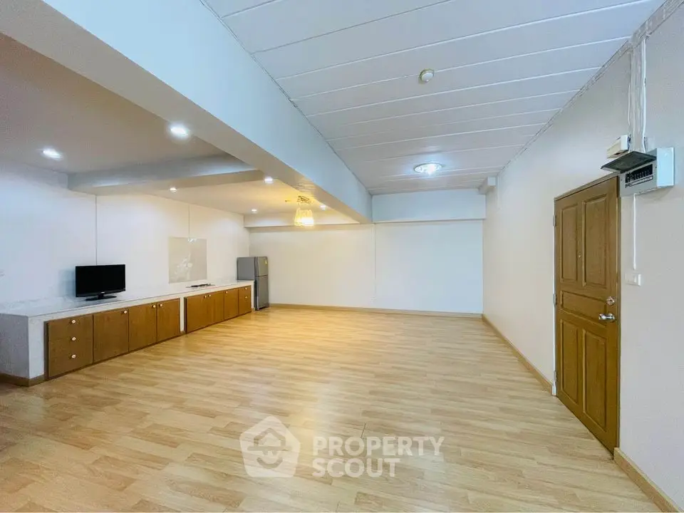 Spacious open-plan living area with wooden flooring and modern lighting, ideal for versatile interior design.