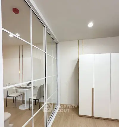 Modern interior with sleek white furniture and mirrored sliding doors in a cozy living space.