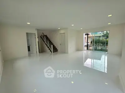 Spacious modern living room with glossy white floors and staircase, perfect for family gatherings.