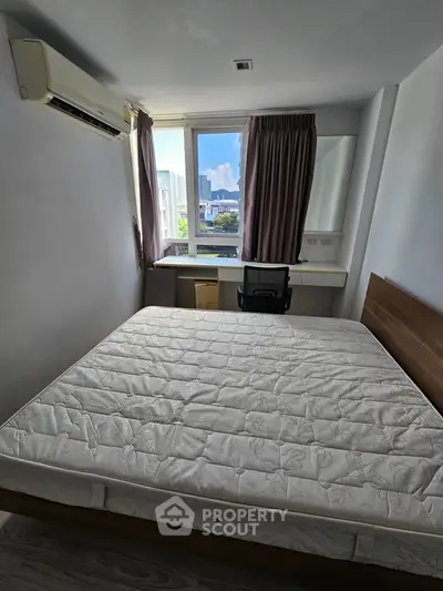 Cozy bedroom with large window and city view, featuring a comfortable bed and study desk.