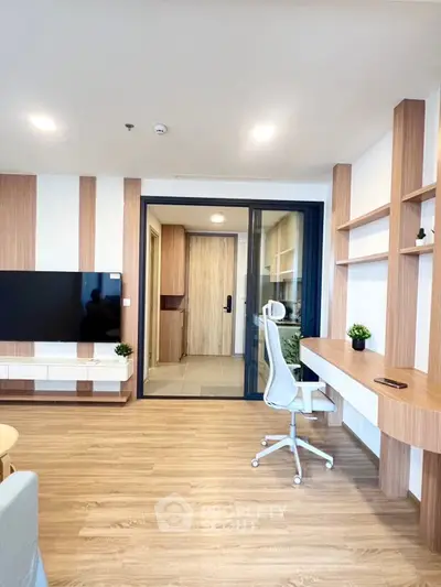 Modern living room with stylish wooden flooring and built-in shelves, featuring a sleek TV setup and ergonomic chair.