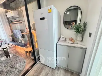 Modern living room with sleek fridge and stylish decor in a contemporary apartment.