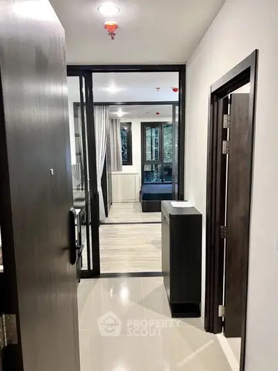 Modern apartment entrance with sleek design and glass partition leading to living area.