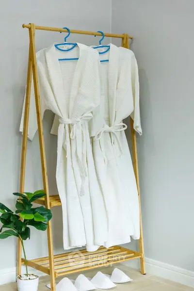 Elegant bathroom with stylish robes on wooden rack and modern decor