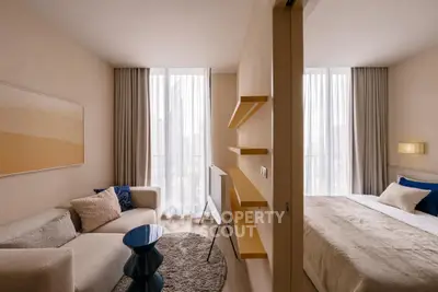 Modern living room with cozy sofa and stylish bedroom in open layout apartment.