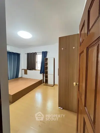 Spacious bedroom with wooden flooring and ample natural light, featuring a minimalist design and cozy atmosphere.