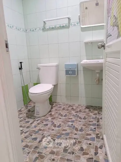 Compact bathroom with tiled floor and essential fixtures, ideal for small spaces.