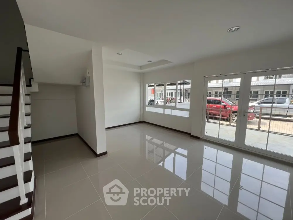 Spacious modern living room with large windows and glossy tiled floor