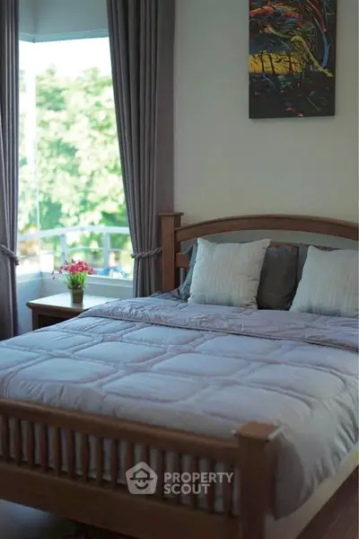 Cozy bedroom with wooden bed frame and large window view