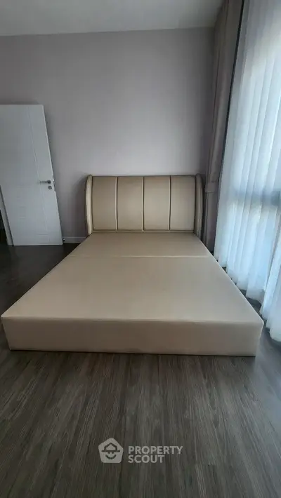 Spacious bedroom with elegant bed and floor-to-ceiling windows for natural light.