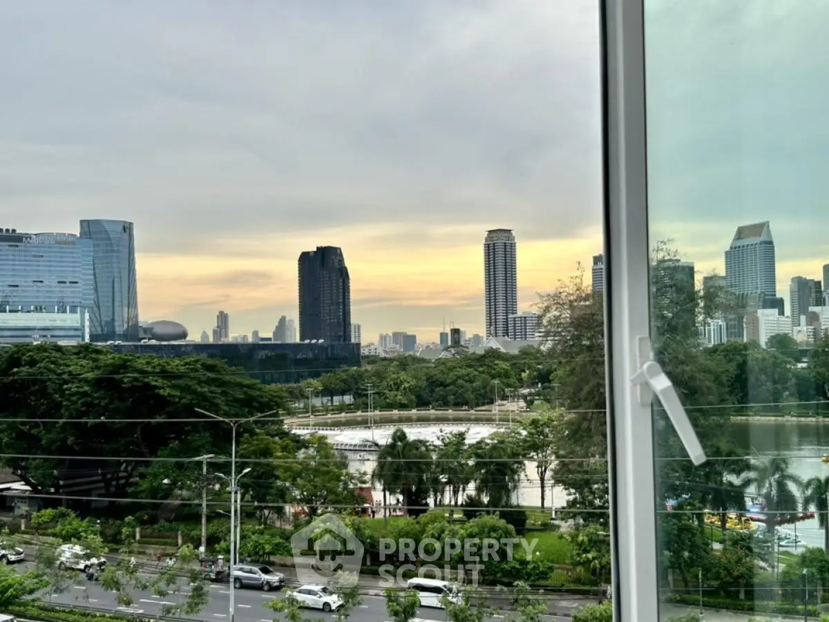 Stunning cityscape view from a modern apartment window overlooking lush greenery and skyline.