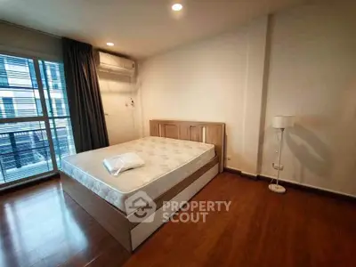 Spacious bedroom with wooden flooring and large window in modern apartment